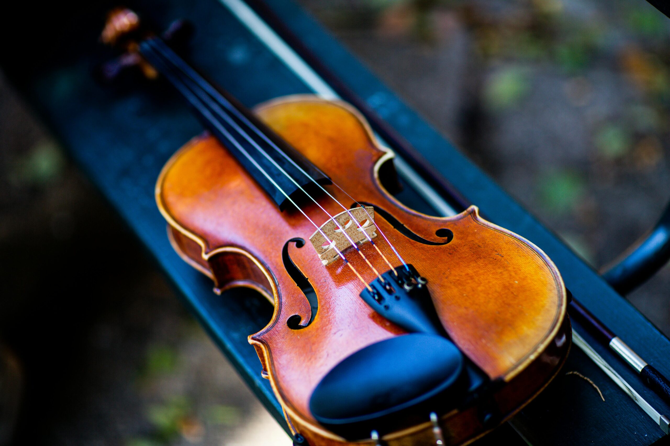 A detailed close-up of a classic violin resting on a dark surface.